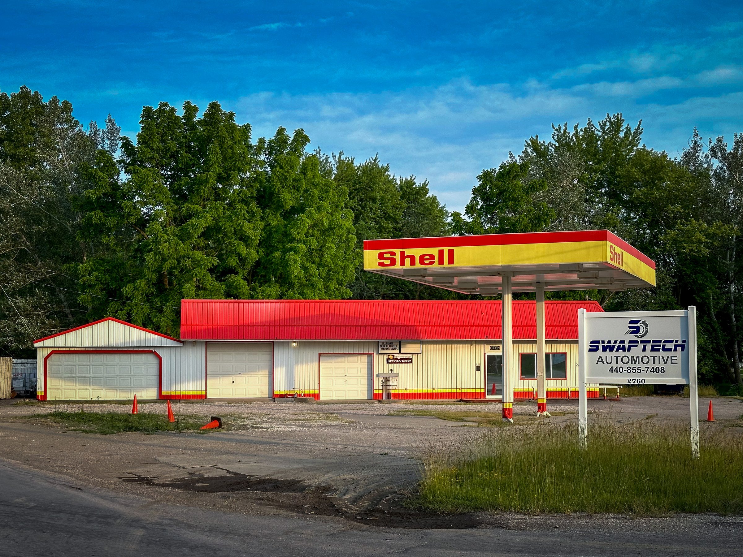 Rural gas station with red roof and Shell canopy, rebranded as SwapTech Automotive